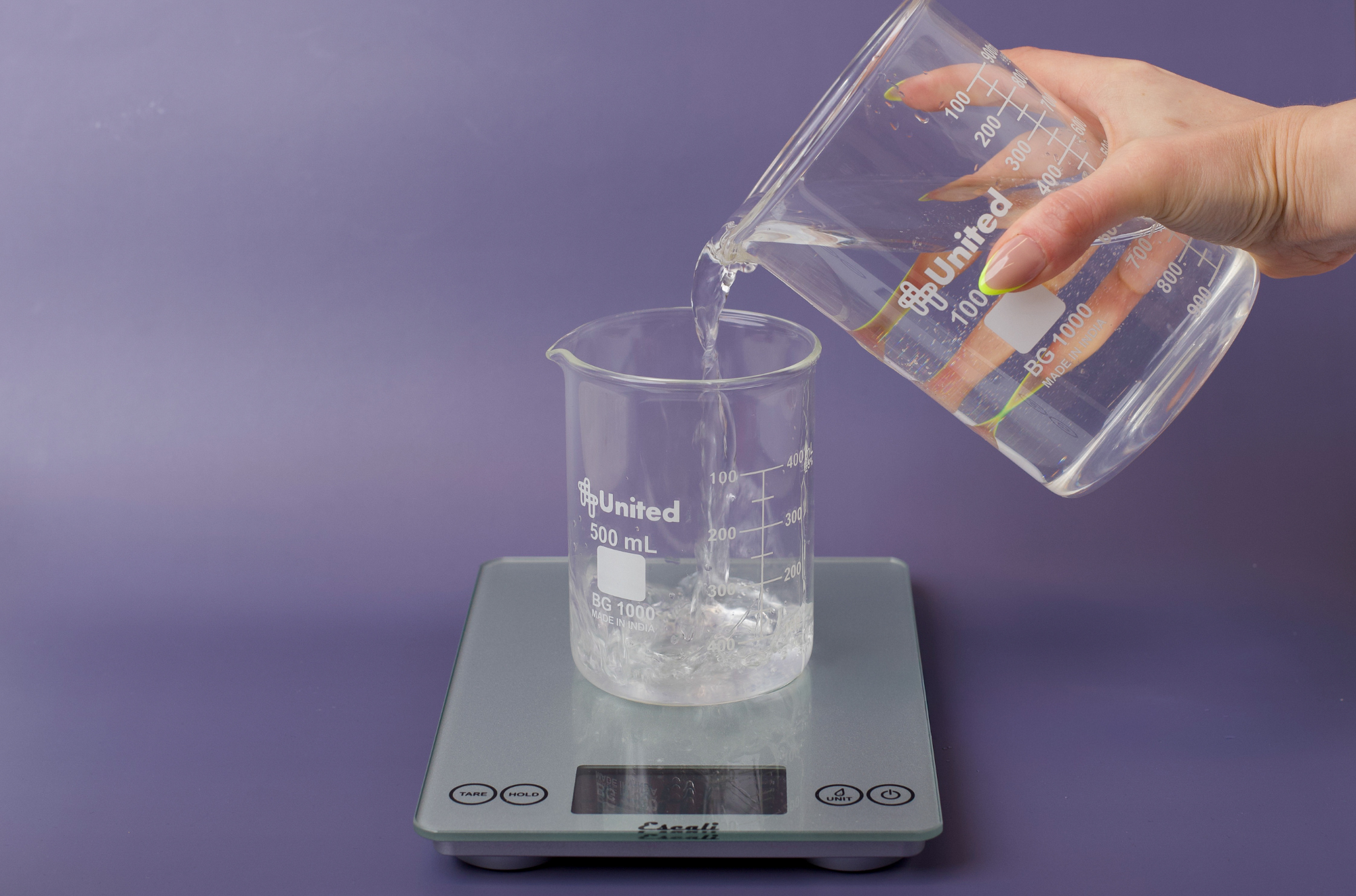 Pouring water into a glass container on a scale.